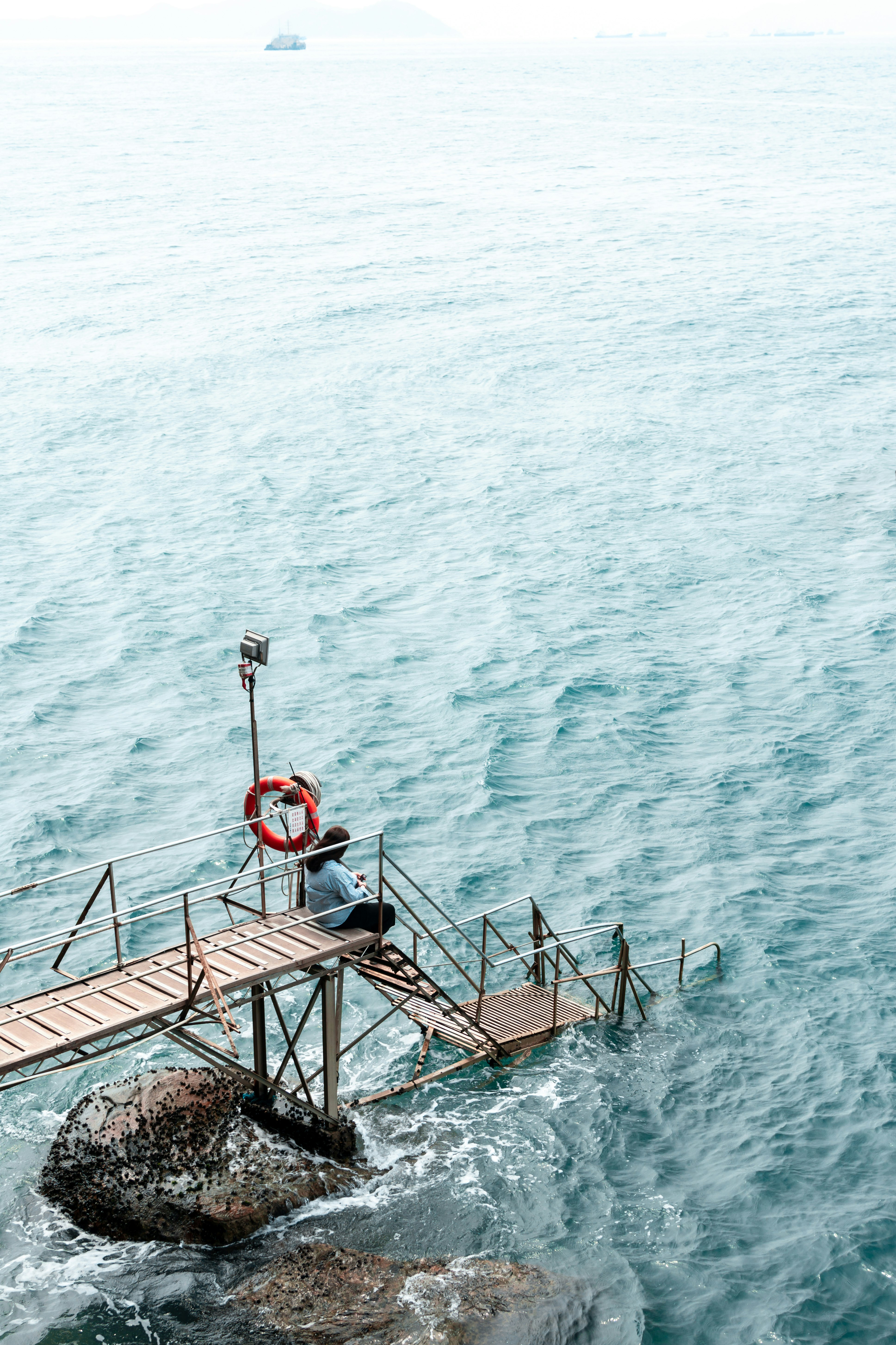 aerial view photography of woman sitting on beach dock